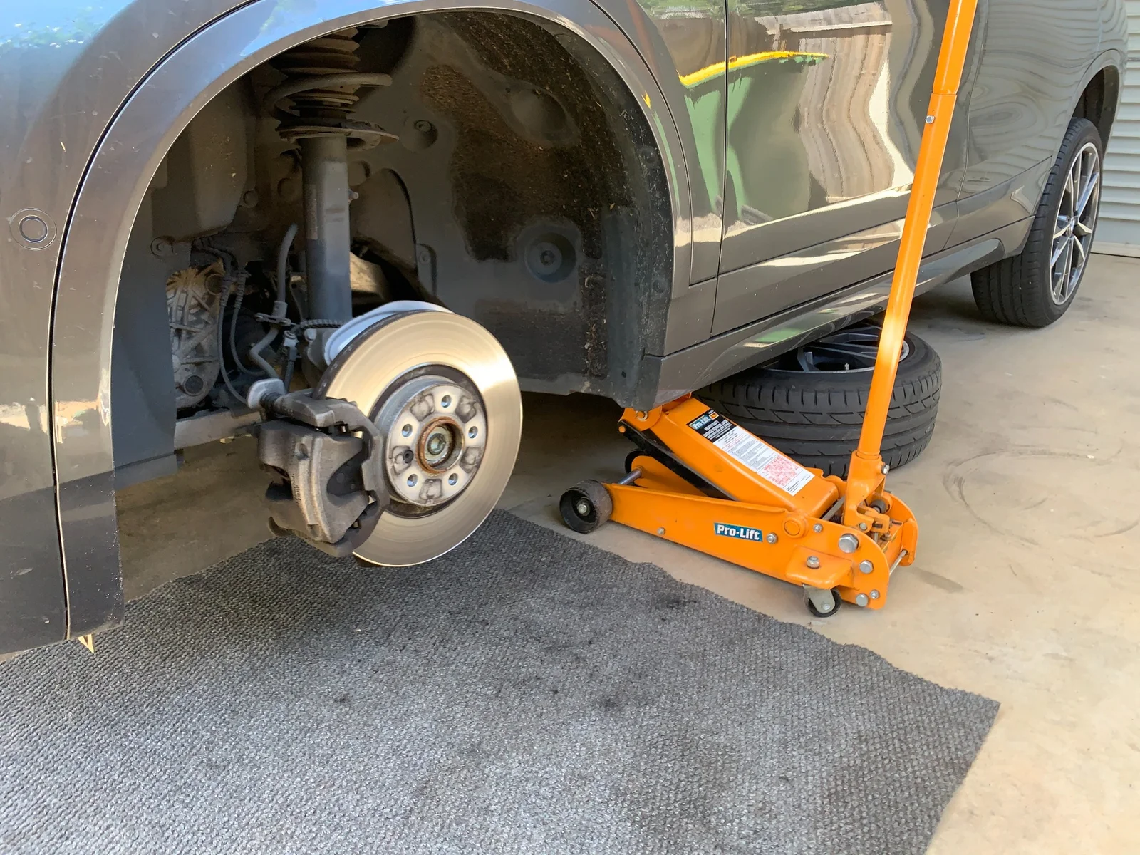 BMW X2 wheel removed for brake disc and caliper inspection on hydraulic jack