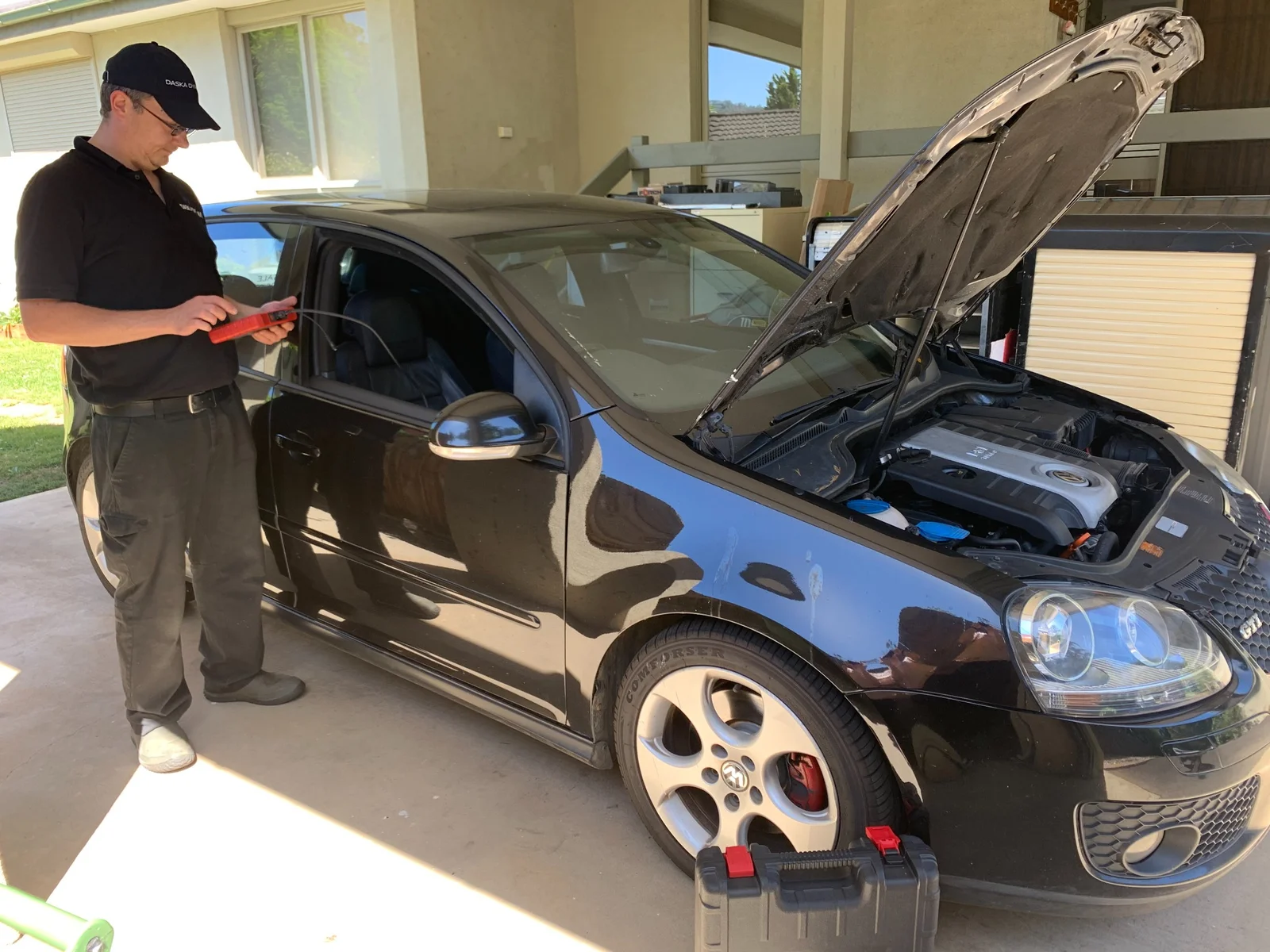 Mechanic performing OBD diagnostic testing on a Volkswagen GTI in workshop